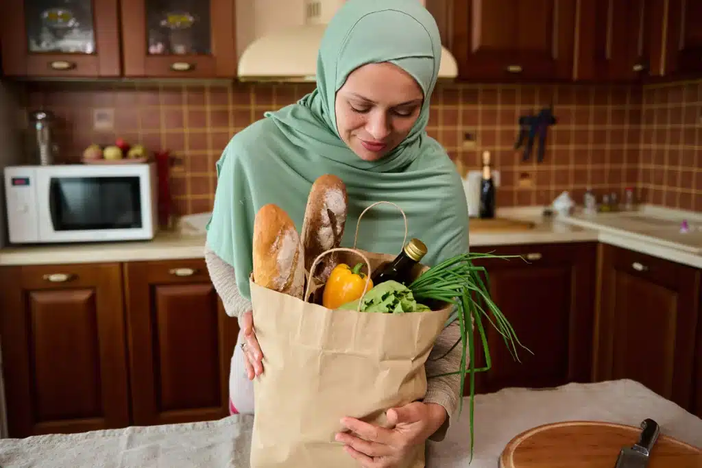 woman setting a bag of groceries down on a kitchen counter